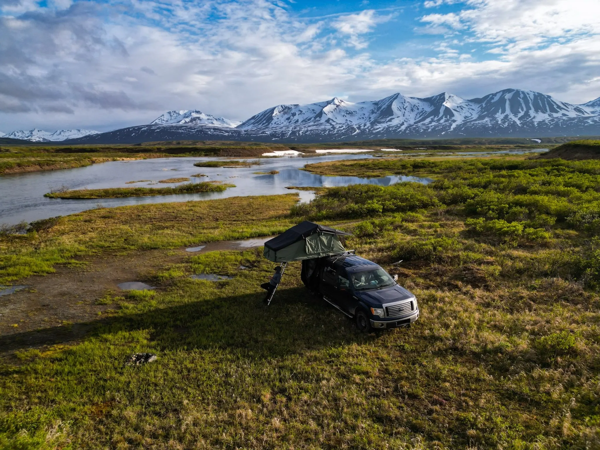 Rooftop-tent truck camping in front of snowy mountains